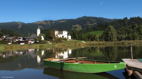 a green boat sitting in the water near a village at Haus Goldeggblick in Goldegg