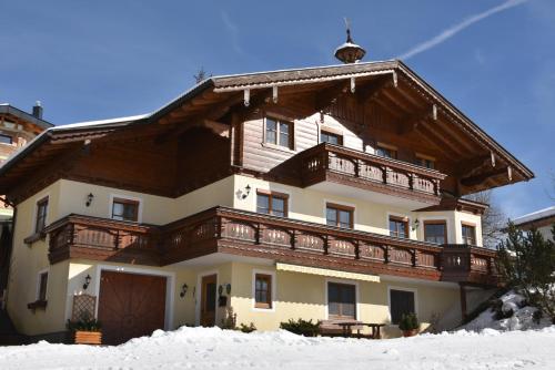 a large house with a wooden roof in the snow at Haus Goldeggblick in Goldegg