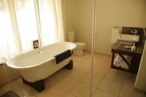 a bathroom with a tub and a toilet and a sink at York Lodge in Harare