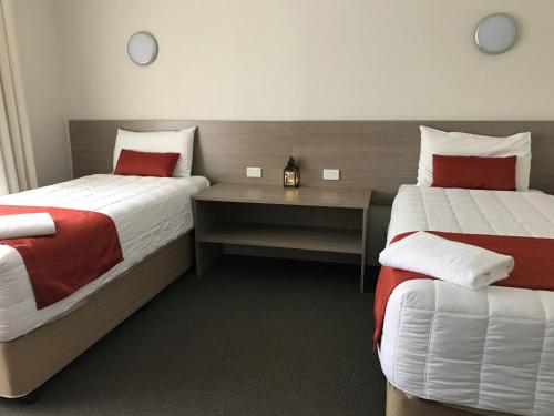 a hotel room with two beds and a desk at Acacia Motor Lodge in Coonabarabran