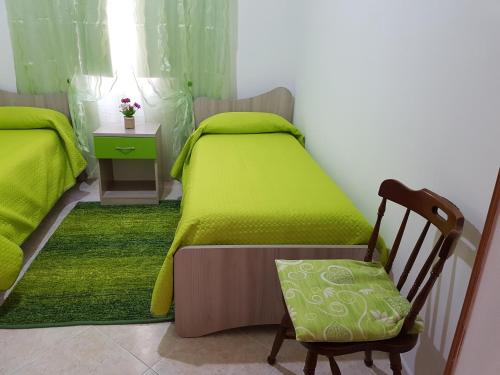 una camera con due letti con lenzuola verdi e una sedia di Alla casa di Anna a Trapani