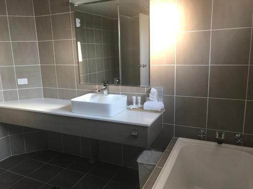 a bathroom with a sink and a mirror and a tub at Acacia Motor Lodge in Coonabarabran