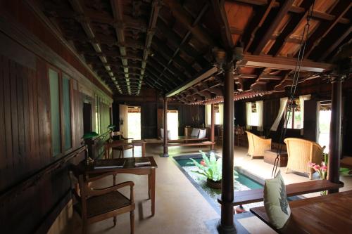 a room with chairs and a pool in a house at Vismaya by Moksha Stays in Turavūr
