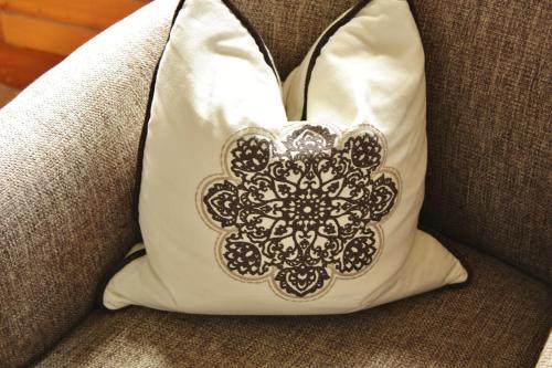 a white pillow with a mandala design on a couch at Parkhotel am Soier See in Bayersoien