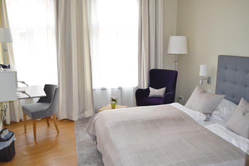 ein Schlafzimmer mit einem Bett und zwei Stühlen und einem Schreibtisch in der Unterkunft Hotel Zum Roten Tore in Lüneburg