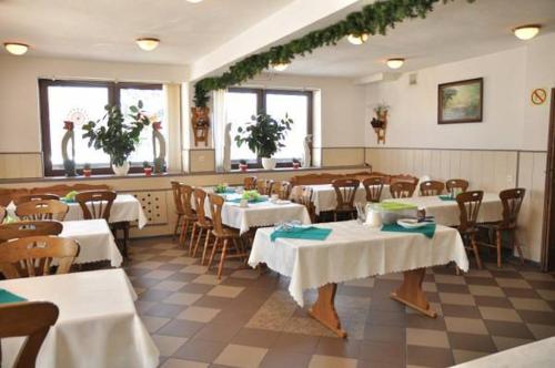 カルパチにあるOśrodek Wypoczynkowy Pod Stokiemの白いテーブルクロスのテーブルと椅子が備わるレストラン