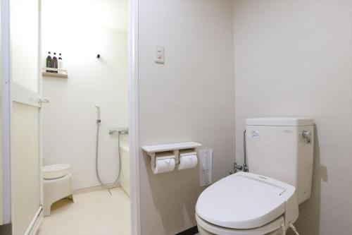 a white bathroom with a toilet and a shower at Hotel Hokke Club Fukuoka in Fukuoka