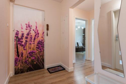 einen Flur mit einem Gemälde lila Blumen an der Wand in der Unterkunft P&O Apartments Kasprzaka in Warschau