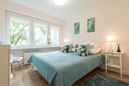 een slaapkamer met een bed en 2 ramen bij P&O Apartments Kasprzaka in Warschau