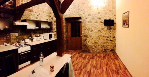 cocina con suelo de madera y pared de piedra en Ansera Residence Sheki, en Sheki