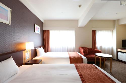 a hotel room with two beds and a chair at Hotel Hokke Club Fukuoka in Fukuoka