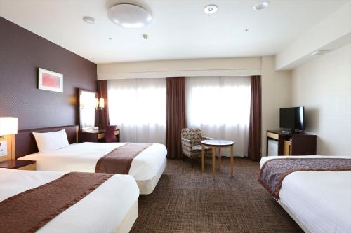 a hotel room with two beds and a television at Hotel Hokke Club Fukuoka in Fukuoka