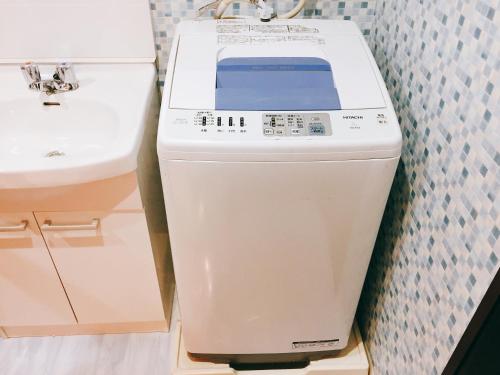 a washing machine in a bathroom next to a sink at Guest House Fukuoka W001 in Kasuga