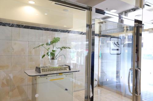 a bathroom with a glass shower with a plant on a counter at Hotel Hokke Club Fukuoka in Fukuoka