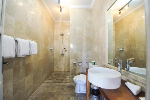 a bathroom with a sink and a toilet at Bali Court Hotel & Apartment in Legian