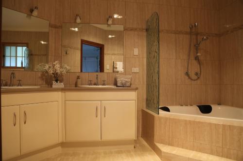 ein Badezimmer mit einer Badewanne, 2 Waschbecken und einer Badewanne in der Unterkunft BellbirdHill Bed & Breakfast in Wingham