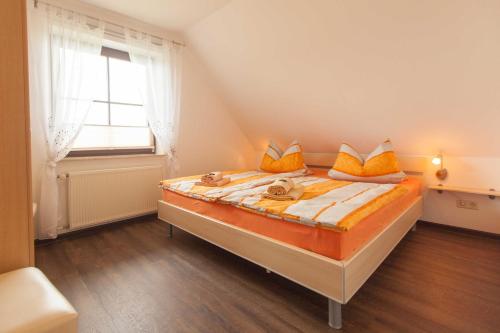 Groß ZickerにあるFerienwohnung Sonnenaufgangのベッドルーム1室(オレンジ色の枕と窓付)