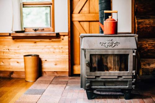 a stove with a red container on top of it at SUNNSNOW Loghouse in Otari