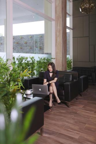 a woman sitting on a couch with a laptop at Aston Batam Hotel & Residence in Nagoya