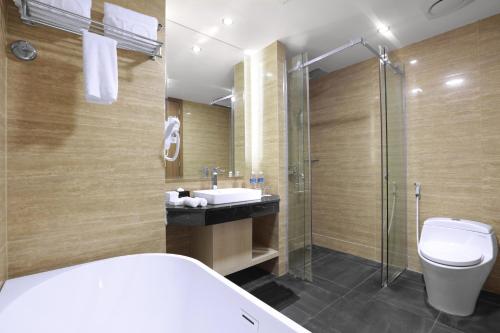 a bathroom with a toilet and a sink and a shower at Aston Batam Hotel & Residence in Nagoya