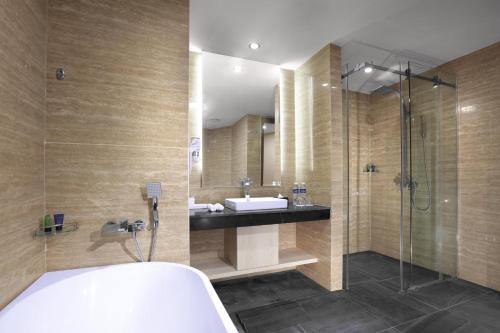 a bathroom with a tub and a sink and a shower at Aston Batam Hotel & Residence in Nagoya
