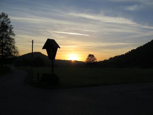 a sunset in a field with a street sign at Ferienwohnung Annele in Hittisau
