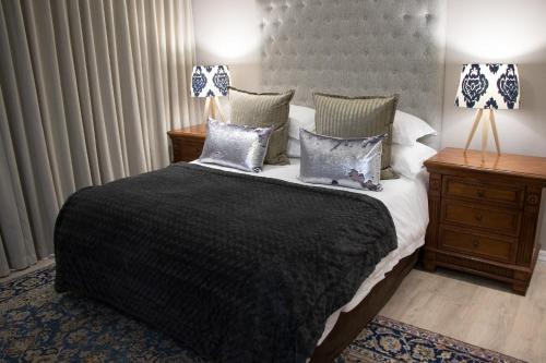 a bedroom with a large bed with pillows and two lamps at A' Queenslin Guesthouse in Paarl
