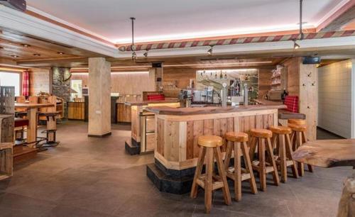 un restaurante con bar con taburetes de madera en Gasthof Kogelalm en Wagrain