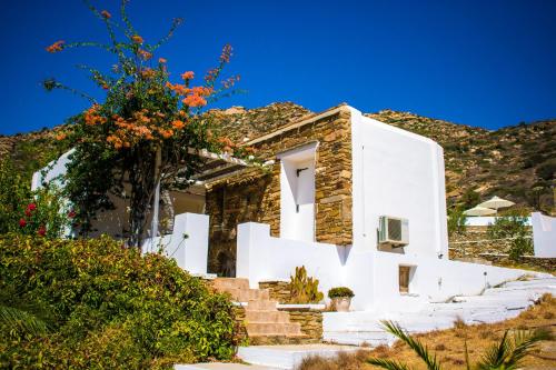 a house with white walls and a tree at Ostria Village in Mylopotas