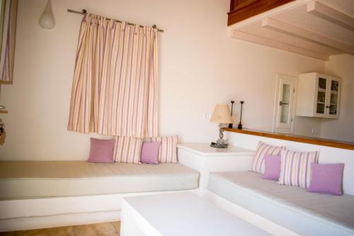 a room with two white benches with purple pillows at Ostria Village in Mylopotas