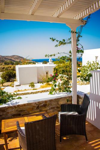 a patio with a table and chairs and a view of the ocean at Ostria Village in Mylopotas