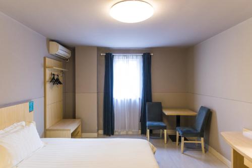 a room with a bed and two chairs and a window at Jinjiang Inn Taiyuan Qingxu County government in Qingxu