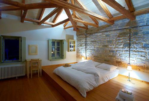 a bedroom with a large bed and a brick wall at Astra Inn in Papigko