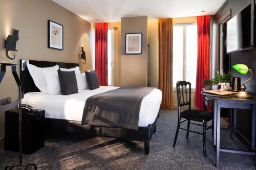 a hotel room with a bed, desk, chair and a lamp at Hotel Le Chat Noir in Paris