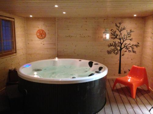 a hot tub in a room with a orange chair at Chalet ChampBenoit in Valmorel