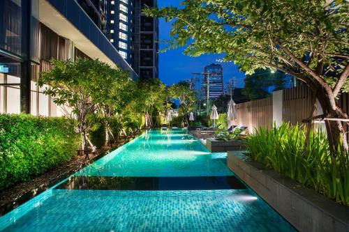 a swimming pool with a fountain in the middle of it at Somerset Ekamai Bangkok - SHA Plus Certified in Bangkok