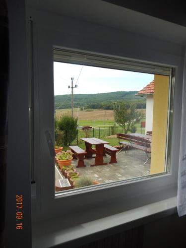 a window with a view of a picnic table and benches at Tündér Szálló Eplény in Eplény