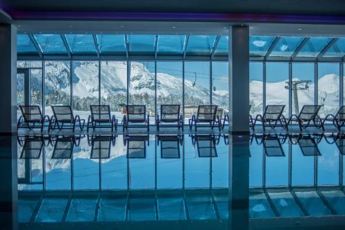 a pool with chairs and a view of the mountains at Hotel Almschlössl & Schrotteralm in Obertauern