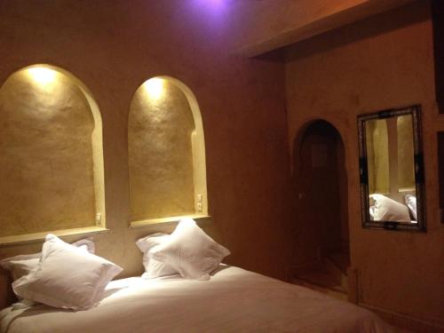 a bedroom with a bed with white pillows and two windows at Kasbah Titrit & Spa in Aït Ben Haddou