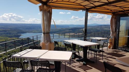 a patio with tables and chairs and a view of a river at Le Casette di Civitella la casa di Nonna Giulia in Civitella Del Lago