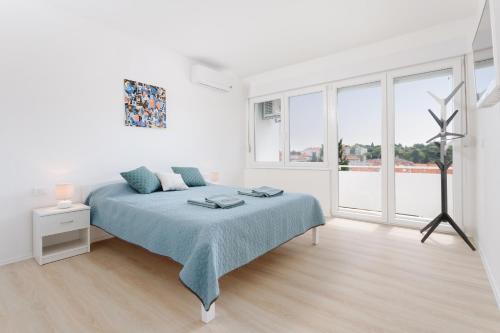 a white bedroom with a bed and a large window at Botun Apartman free parking in Pula