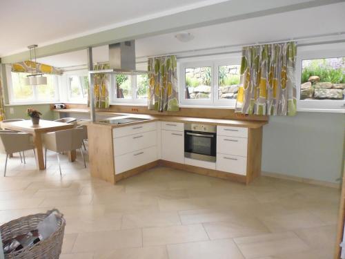 a kitchen with white cabinets and a table and windows at Bungalow A in Börnecke