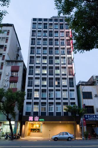 a tall building with a car parked in front of it at Songshan Hotel in Kaohsiung