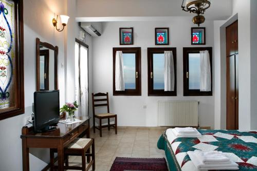a living room with a bed and a desk with a tv at Archontiko Elda in Agios Dimitrios