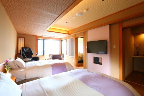 a hotel room with two beds and a flat screen tv at Hotel Higashidate in Yamanouchi