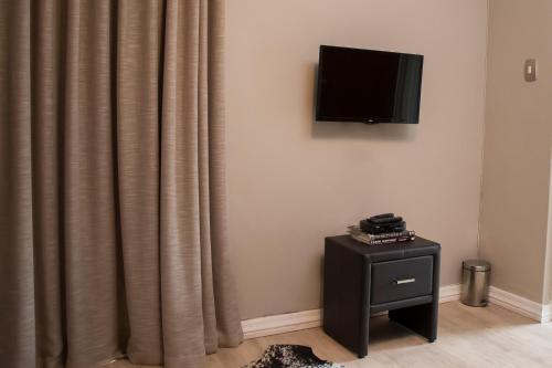 a room with a curtain and a television on a wall at A' Queenslin Guesthouse in Paarl