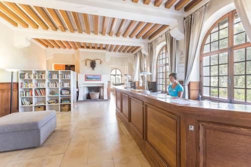 eine Frau, die an einer Bar in einem großen Raum sitzt in der Unterkunft Résidence Pierre & Vacances Le Domaine de Bordaberry in Urrugne