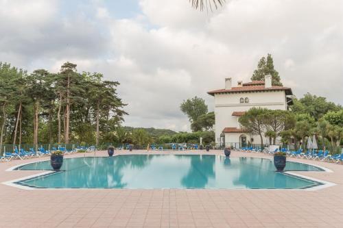 une piscine devant un immeuble dans l'établissement Résidence Pierre & Vacances Le Domaine de Bordaberry, à Urrugne