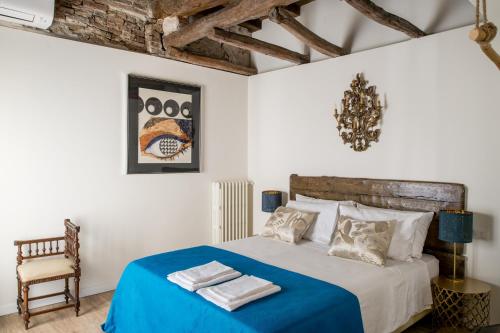a bedroom with a bed with a blue blanket and a chair at L'8 Boutique Concept Apartments in Bologna