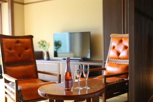 a room with a table with two glasses and a bottle of wine at Hotel Higashidate in Yamanouchi